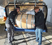 (v.l.n.r.) Destillateurmeister Hans Kemenater und SLYRS-Geschäftsführer Anton Stetter platzieren eines der 24 Whisky-Fässer auf dem Sessellift.